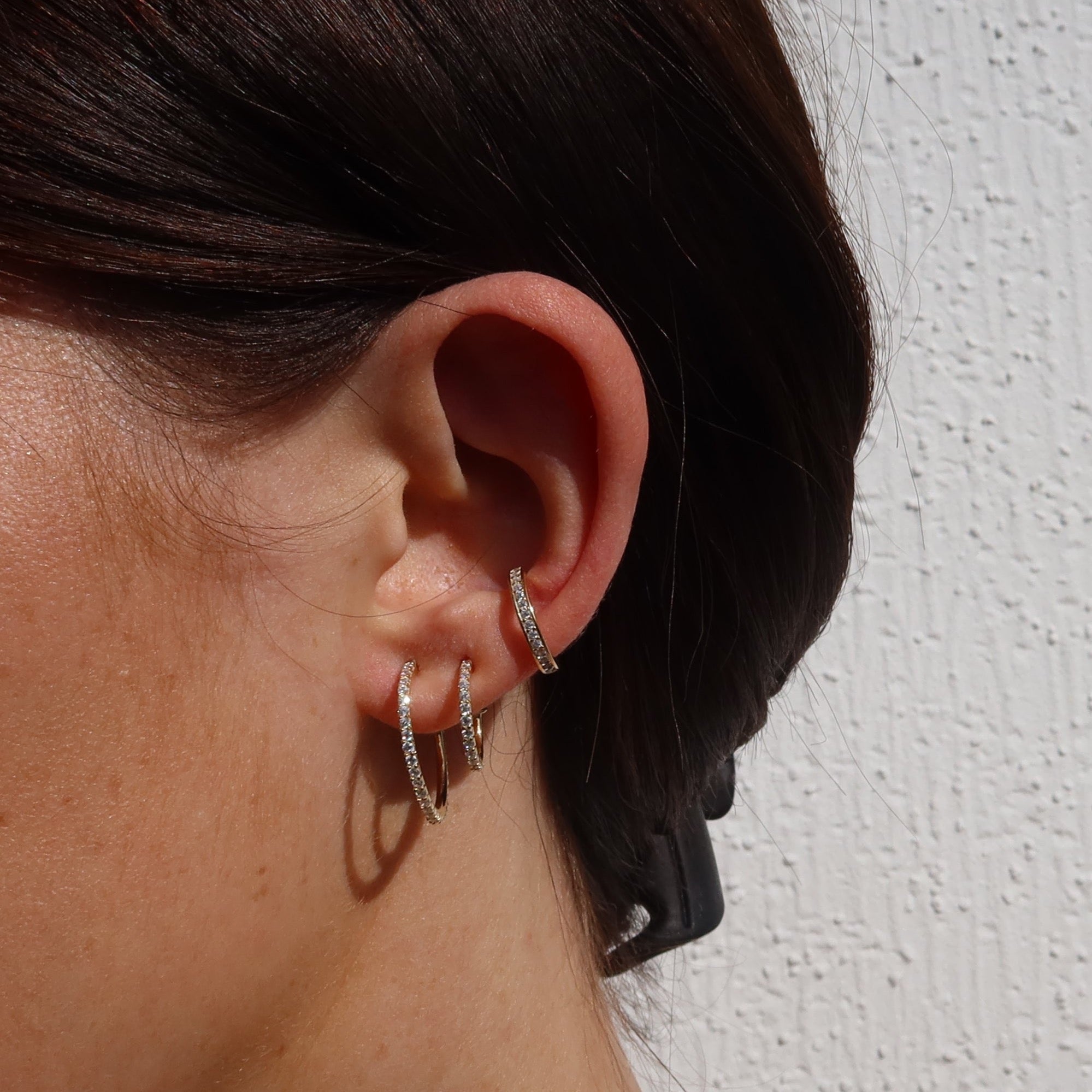 Funkelnde, dünne Hoop-Creolen M mit Zirkonia im Ear-Stack einer Frau.