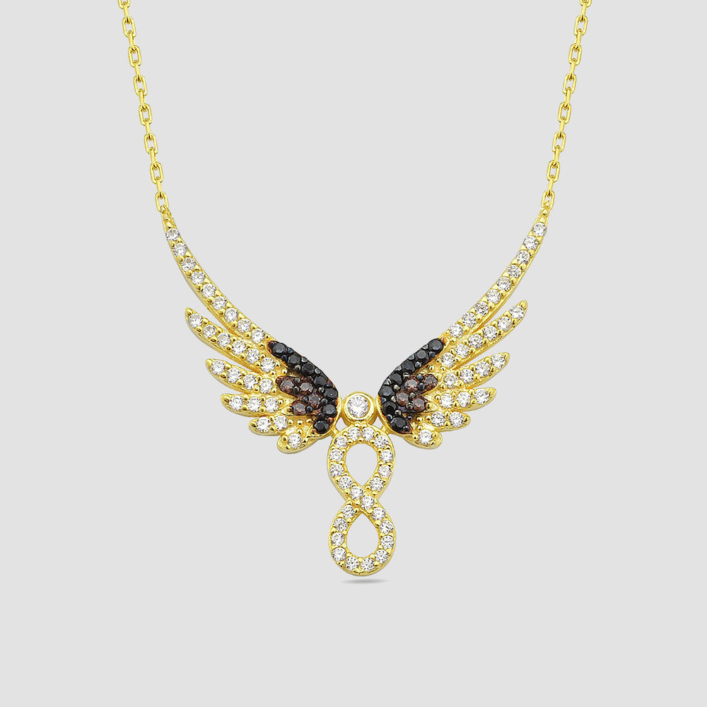 Infinity Angel Wings Halskette in Gold, mit weißen und schwarzen Zirkonia-Steinen auf hellem Hintergrund