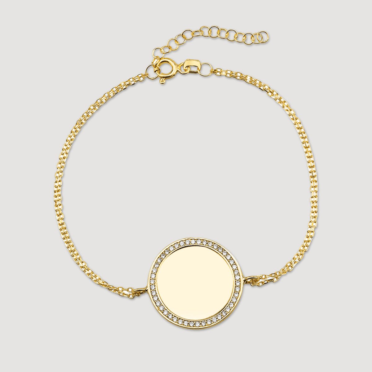 Mirror Gravur Armkette Gold mit runder Gravurplatte und Zirkonia-Rand auf hellem Hintergrund.
