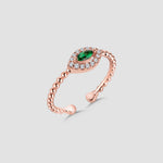 Navette Emerald Ring rosévergoldet mit grünem Zirkonia und funkelnden Zirkonia-Steinen auf grauem Hintergrund.