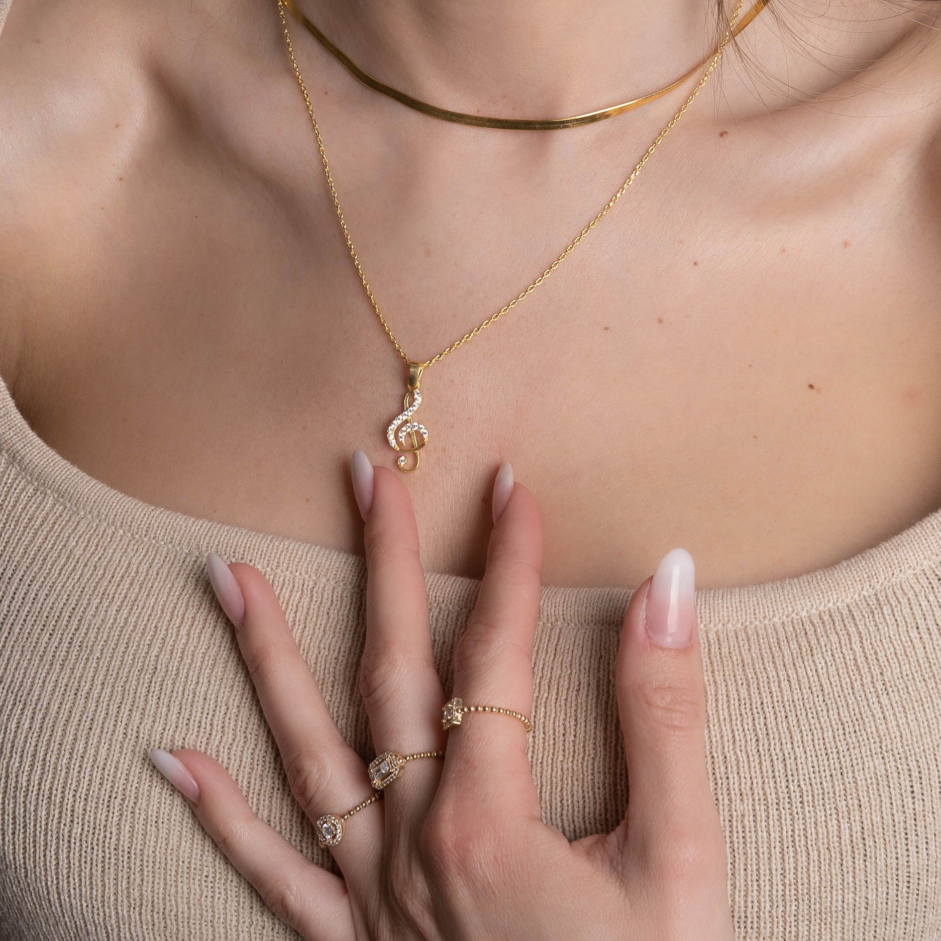 Notenschlüssel Kette Gold am Hals getragen, Anhänger mit Zirkonia im Layering-Look.