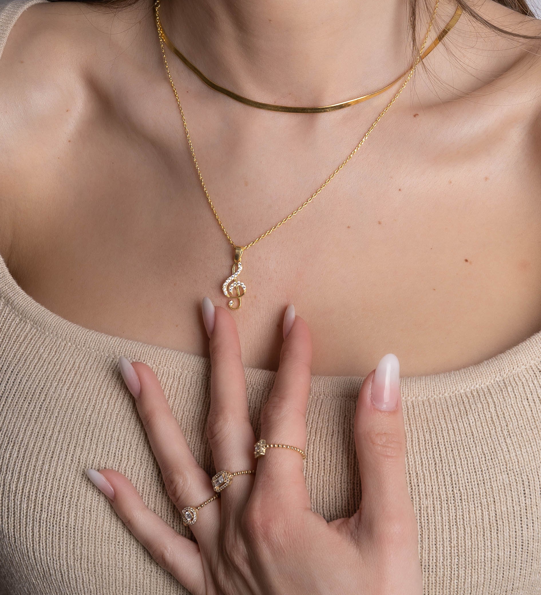 Notenschlüssel Kette Rosé & Silber als zarter Blickfang am Dekolleté, Styling mit Goldschmuck.