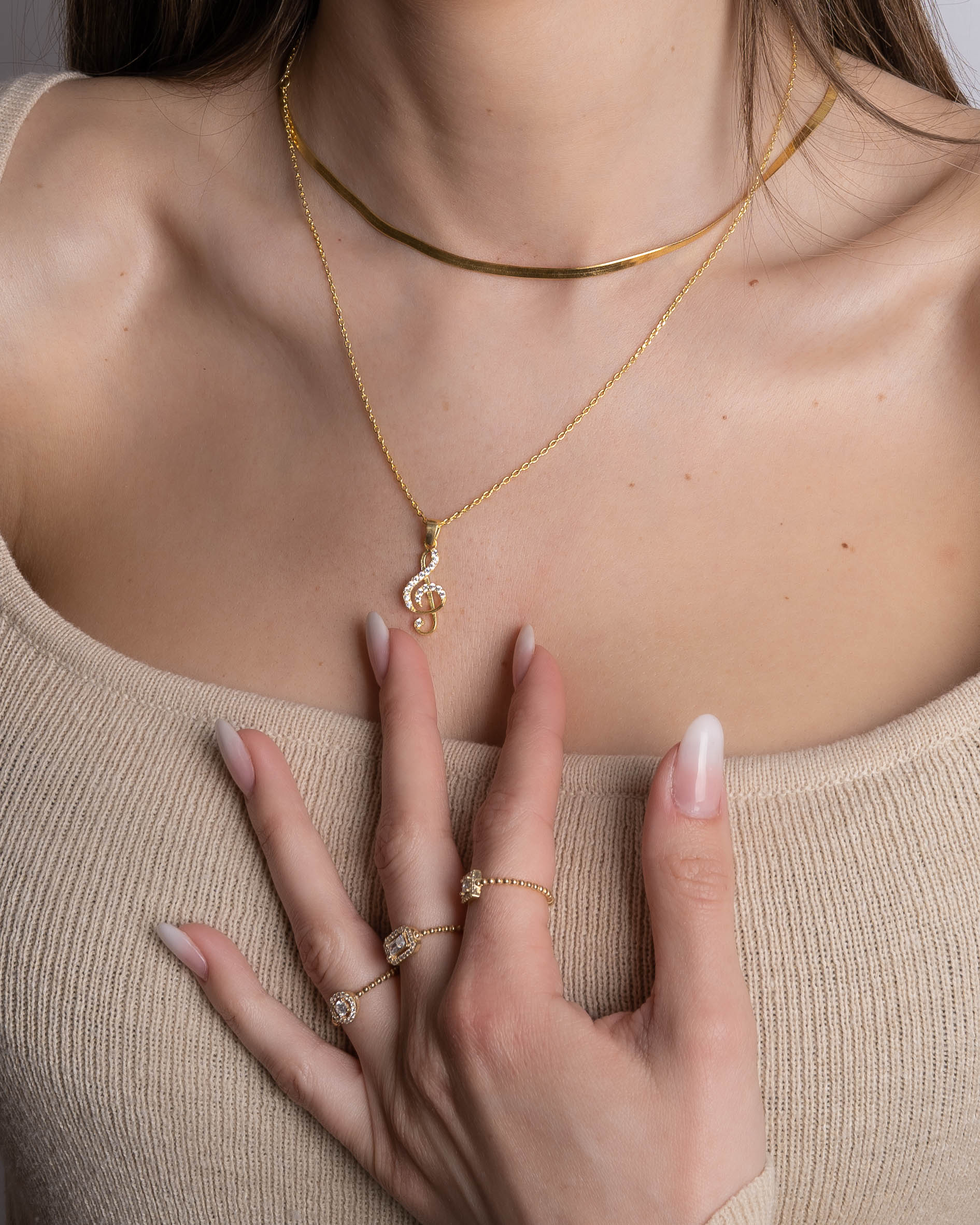 Notenschlüssel Kette Rosé & Silber als zarter Blickfang am Dekolleté, Styling mit Goldschmuck.