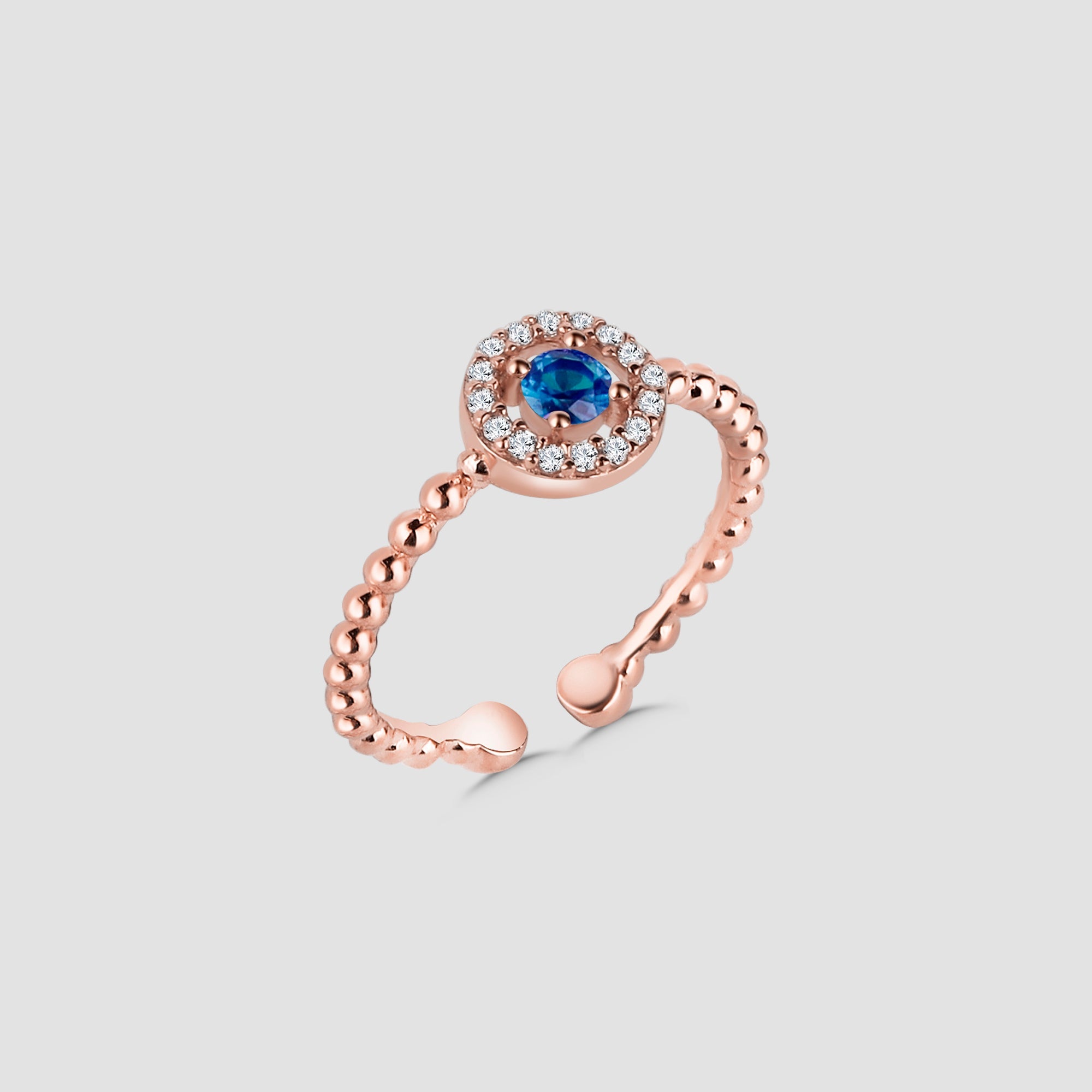 Round Saphir Ring Shiny Wreath in Rosévergoldet mit blauem Zirkonia und Zirkonia-Halo auf grauem Hintergrund.