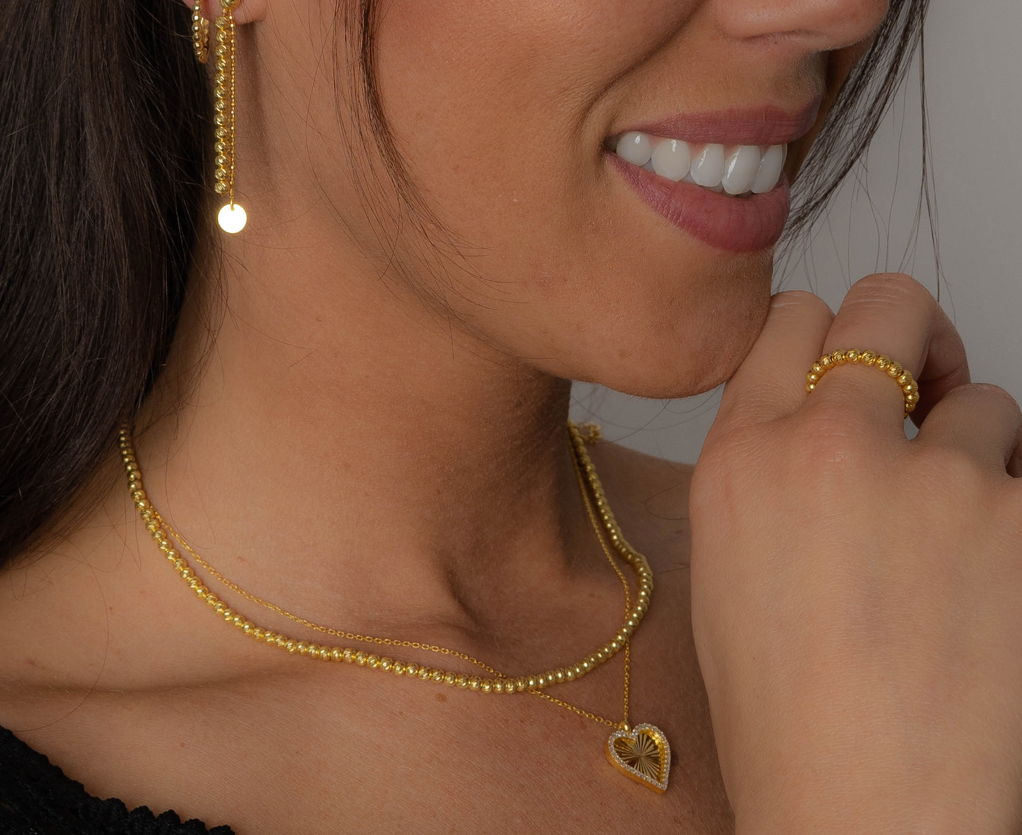 Model trägt Shiny Balls X Ring Gold – glänzender Kugelring kombiniert mit goldener Kette und Ohrringen.