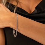 Tennis Armband Silber mit funkelnden Zirkonia am Handgelenk einer Frau im Abendoutfit.